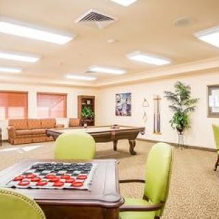 A spacious recreation room featuring a pool table, checkers game, comfortable seating, and vibrant decor.