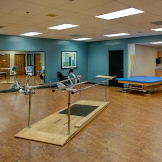 A well-equipped physical therapy room featuring exercise equipment and a treatment area.