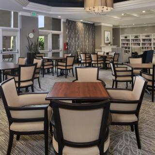 A stylish dining area featuring multiple tables and chairs, elegant lighting, and a cozy atmosphere.