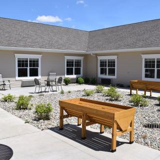 A landscaped courtyard featuring raised garden beds and outdoor seating at a residential building.