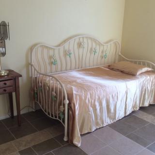 A bedroom with a vintage-style daybed and a small wooden side table.