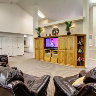 A spacious living room with cozy leather sofas and a large television in an entertainment center.