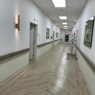 A well-lit hospital hallway with artwork on the walls and polished flooring.