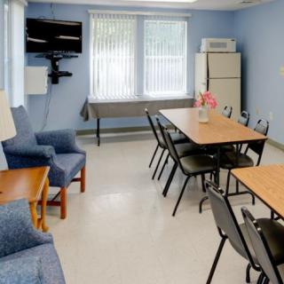 A meeting room with a conference table, chairs, a TV, refrigerator, and sofa against blue walls.