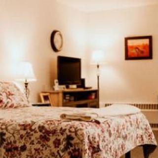 A cozy bedroom with warm lighting and a floral quilt on the bed.