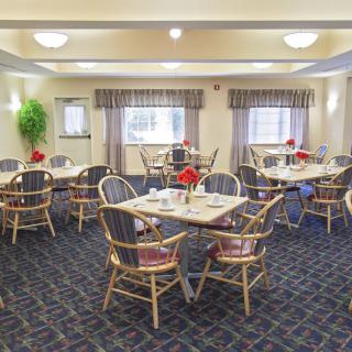 A well-lit dining room with multiple tables and chairs arranged neatly.