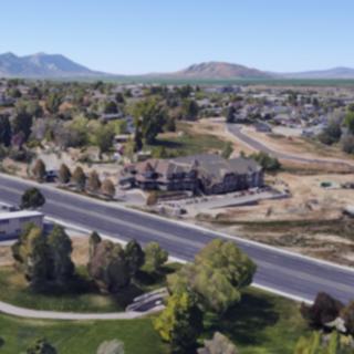 A suburban neighborhood with houses and roads, surrounded by trees with mountains in the background.