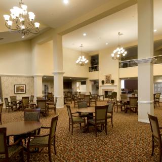 Spacious dining area with elegant chandeliers and neatly arranged tables and chairs.