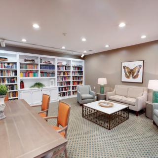 A cozy library with a large bookshelf, comfortable seating, and decorative artwork.