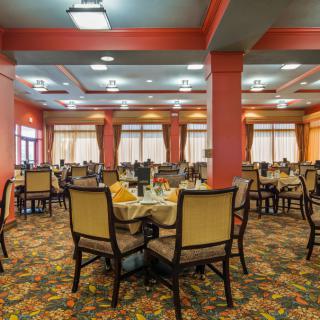 A spacious dining area with well-arranged tables and chairs, featuring warm decor and ample lighting.