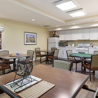 A modern dining and kitchen area with several tables and chairs, designed as a communal space.