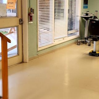 A hospital hallway with medical equipment and a door leading outside.