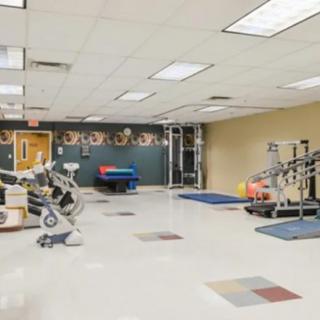 A spacious physical therapy room equipped with various exercise machines and rehabilitation tools.
