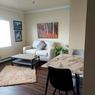 A cozy living room with a sofa, coffee table, and a dining area featuring modern decor.