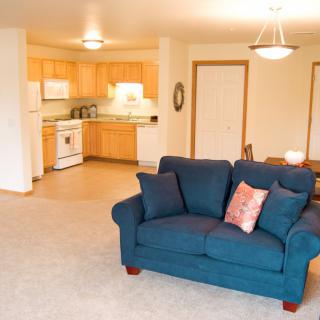 A cozy living area with a blue sofa adjacent to an open kitchen in an apartment.