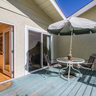 A sunny patio area featuring a round table with chairs and an umbrella, adjacent to a sliding glass door.
