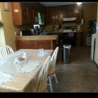 A cozy kitchen with a dining table set for four, surrounded by wooden cabinets and various appliances.