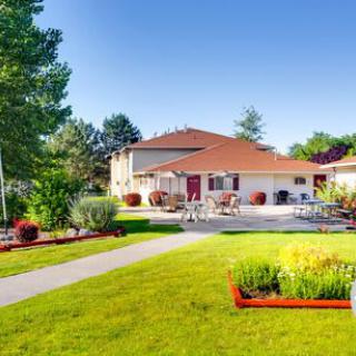 A beautiful house with a well-maintained backyard and garden, featuring a spacious patio and lush green lawn.