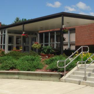 A modern building entrance with landscaped surroundings and stairs leading up.