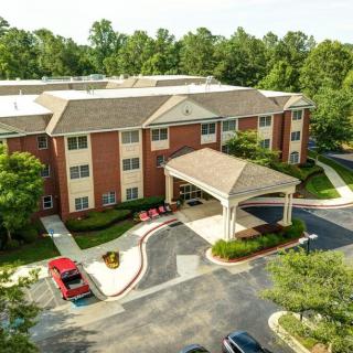 Aerial view of a building with a covered entrance and surrounding parking lot.