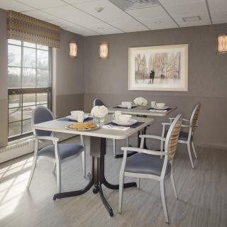 Modern dining room with a minimalist setup, featuring a table set for four near a large window.