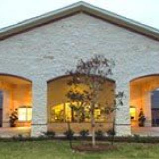 A well-lit building with a symmetrical design and a tree in the foreground.
