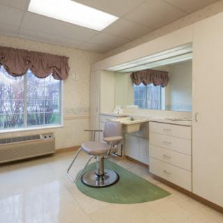 A well-lit salon space featuring a vanity, mirror, and styling chair.