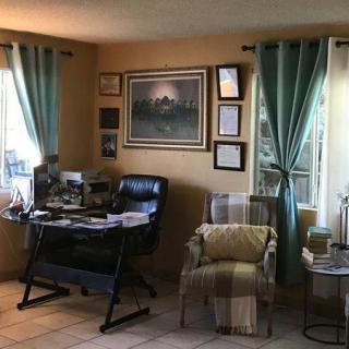 A cozy home office with a desk, chair, and artwork on the walls.