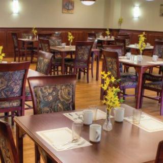 A cozy restaurant dining area with neatly arranged tables and chairs, featuring floral centerpieces and place settings.