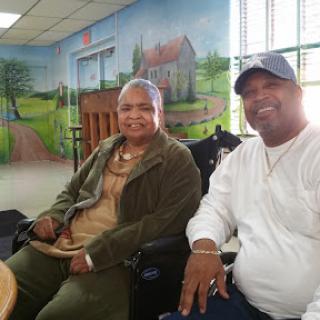 A joyful moment shared between a man and an elderly woman in a community center.