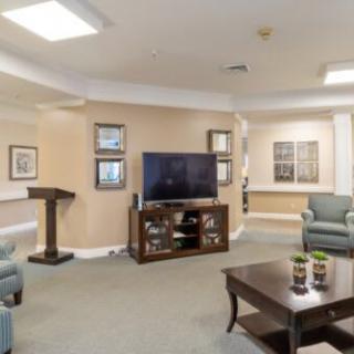 A well-lit living room with comfortable seating, a large television, and a coffee table.