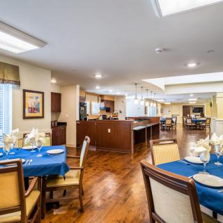 A well-lit dining area with neatly arranged tables and chairs, featuring wooden flooring.