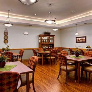A cozy dining room with wooden tables and chairs arranged neatly, featuring warm lighting and tasteful decor.