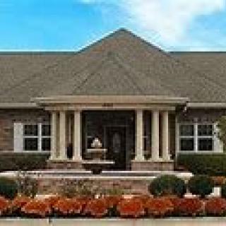 A suburban single-story house with columns and neatly landscaped front yard.