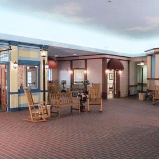 A cozy indoor hallway featuring a seating area with rocking chairs and tables, accented by decorative lamps.