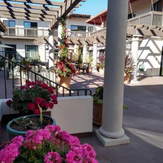 A sunny courtyard adorned with vibrant flowers and elegant architecture.