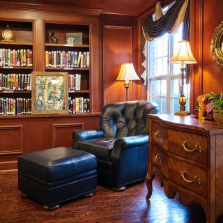 A cozy library corner with a leather armchair and ottoman, surrounded by bookshelves.