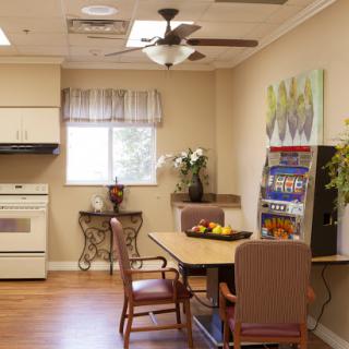 A cozy kitchen and dining area featuring a table with chairs, a ceiling fan, and a vending machine for snacks.