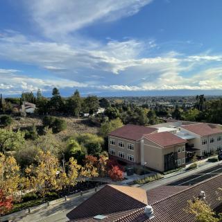 A scenic suburban landscape with buildings, trees, and a clear blue sky.