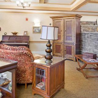 A cozy living room with a piano, armchair, and stone fireplace.