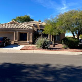 A charming residential home with a lush landscape and a clear blue sky.