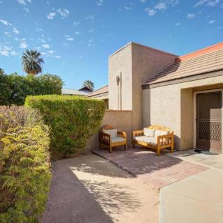 A cozy outdoor patio area with seating arrangements, surrounded by a hedge on a sunny day.