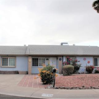A charming blue residential house with a landscaped front yard.