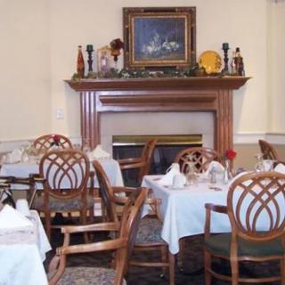 A cozy dining area featuring elegantly set tables and a warm fireplace.
