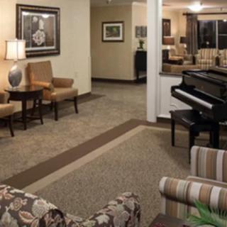 A cozy lobby featuring a grand piano, seating area, and framed artwork.