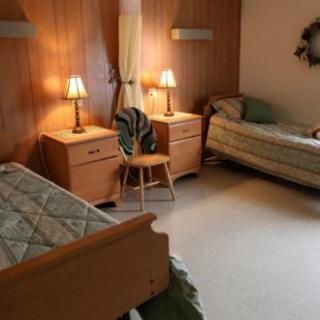 A cozy bedroom with two single beds, wooden furniture, and warm lighting.