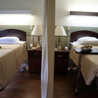 A view of a hotel room featuring two neatly made beds with lamps and nightstands.