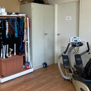 A home gym with a stationary bike and storage for workout gear.