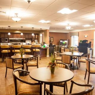 A cozy caf setting with neatly arranged tables and chairs, warmly lit for a welcoming ambiance.