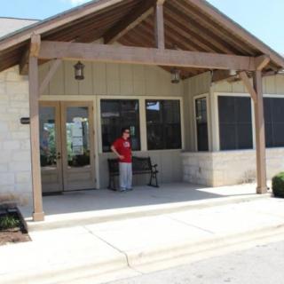 A person standing with a dog in front of a building's entrance.